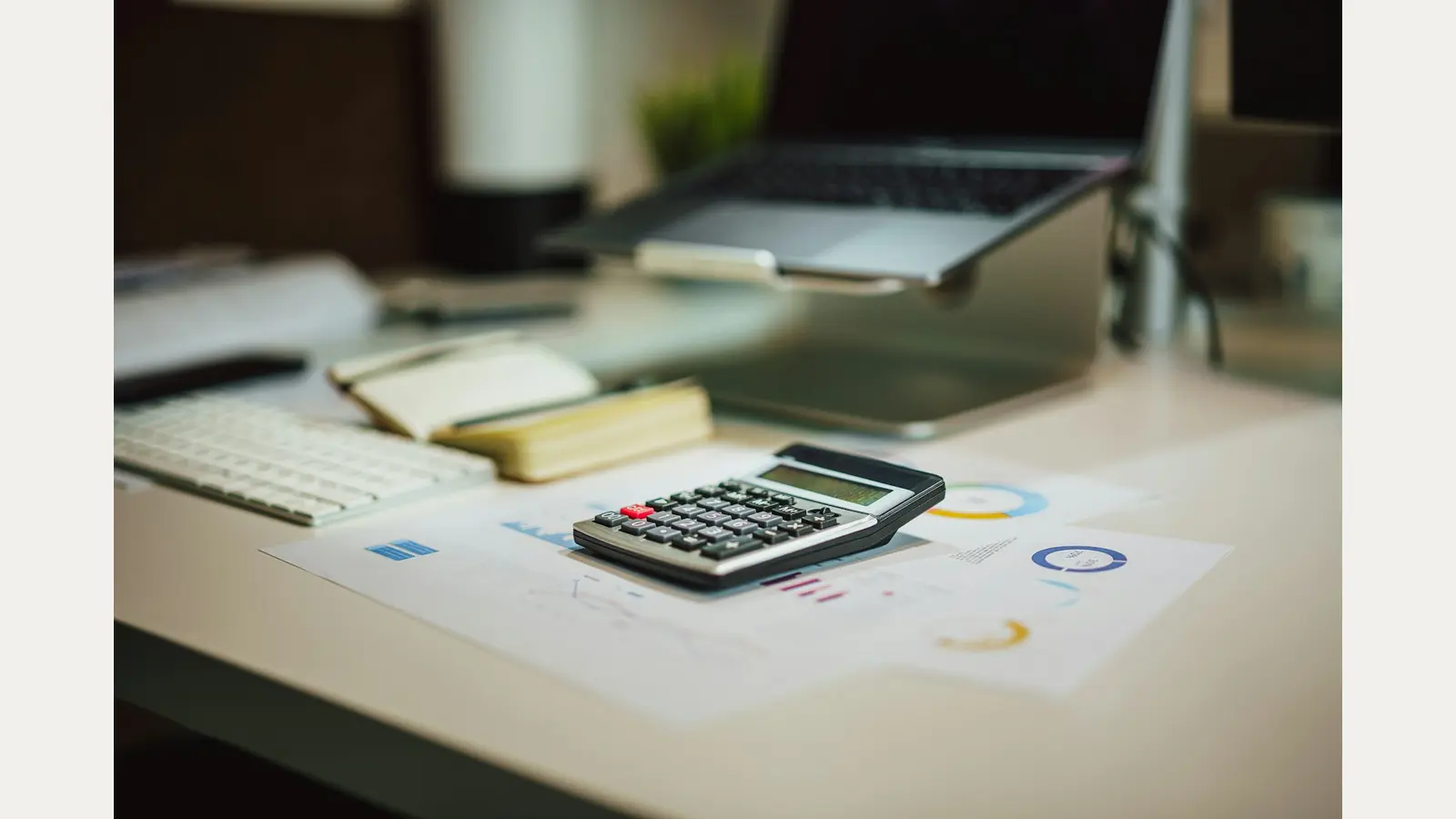Laptop, calculator, notebook and paperwork arranged for checking tax records