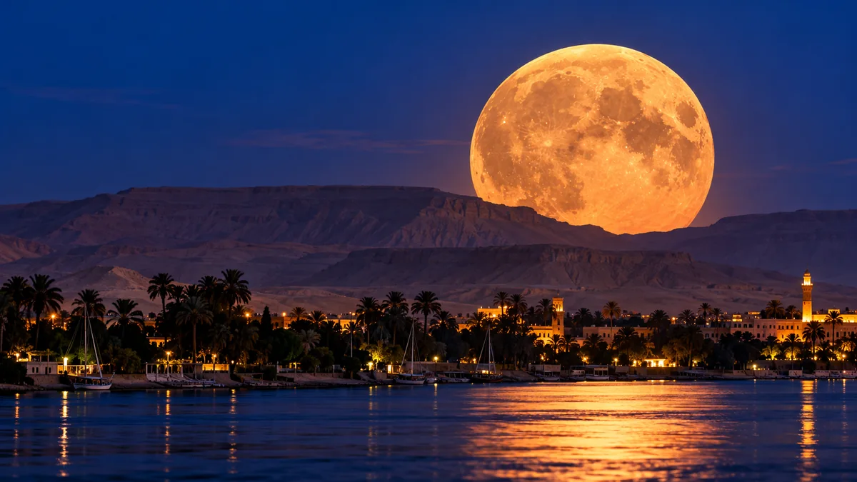 Why Does the Moon Look Enormous Near the Horizon? The Science of the Moon Illusion 1 Illustrative oversized orange Moon rising above a river town and distant mountains at dusk